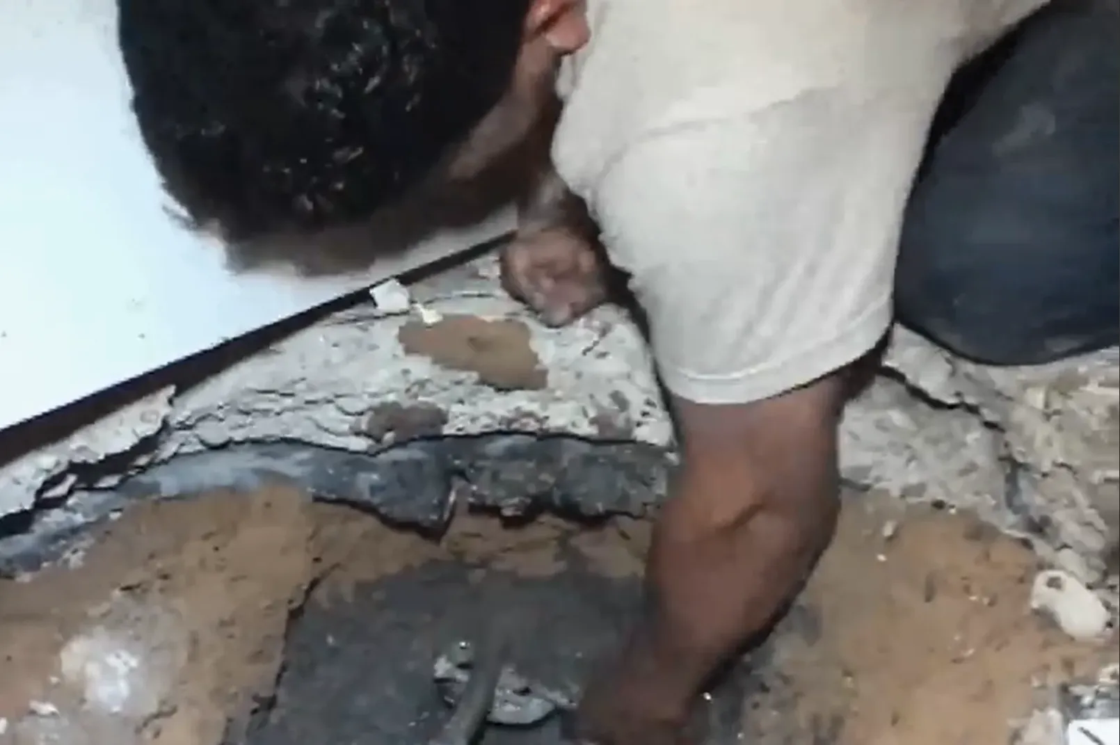 Plumber accessing a slab leak through a small opening in the concrete